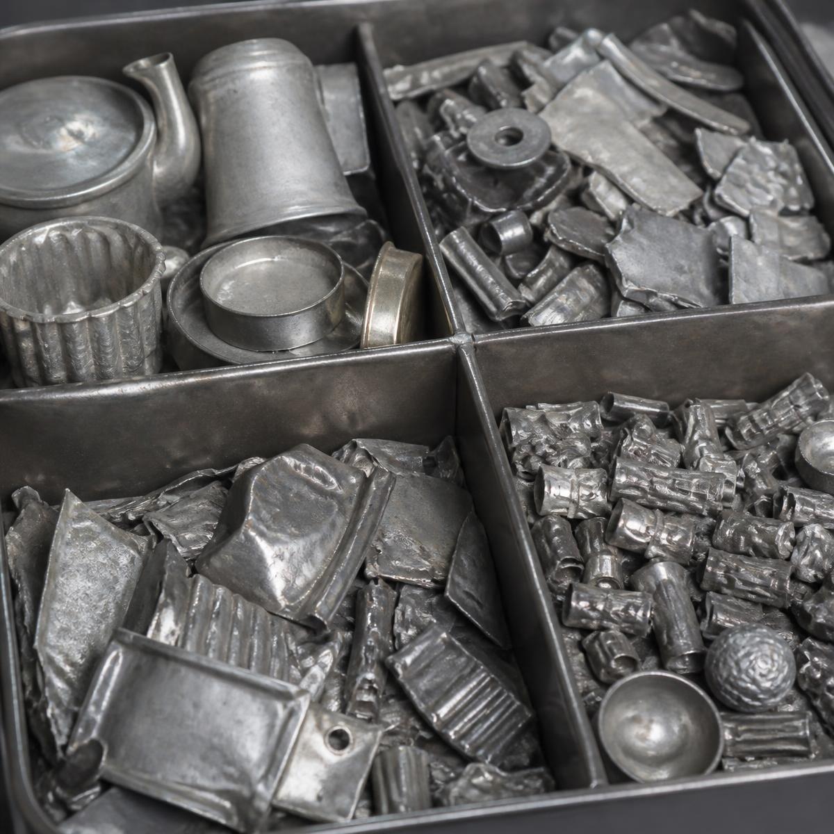 Gesorteerd oud tin en tinlegeringen in een metalen bak