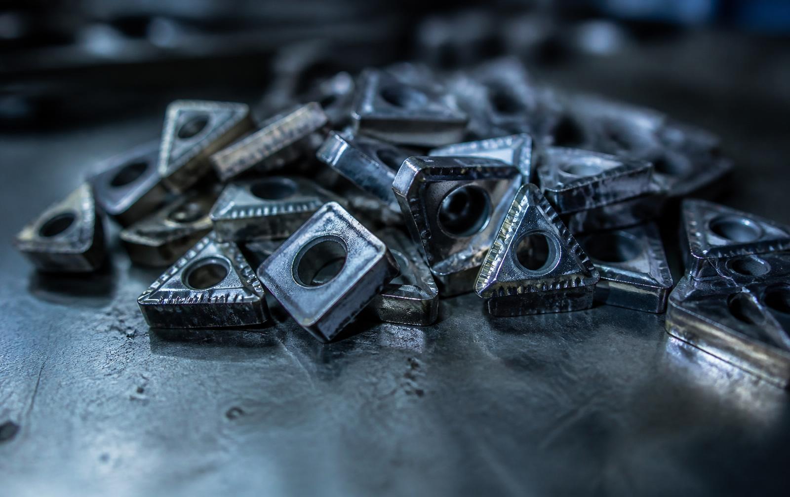 Gebruikte hardmetalen wisselplaten op een werkbank in een machinewerkplaats